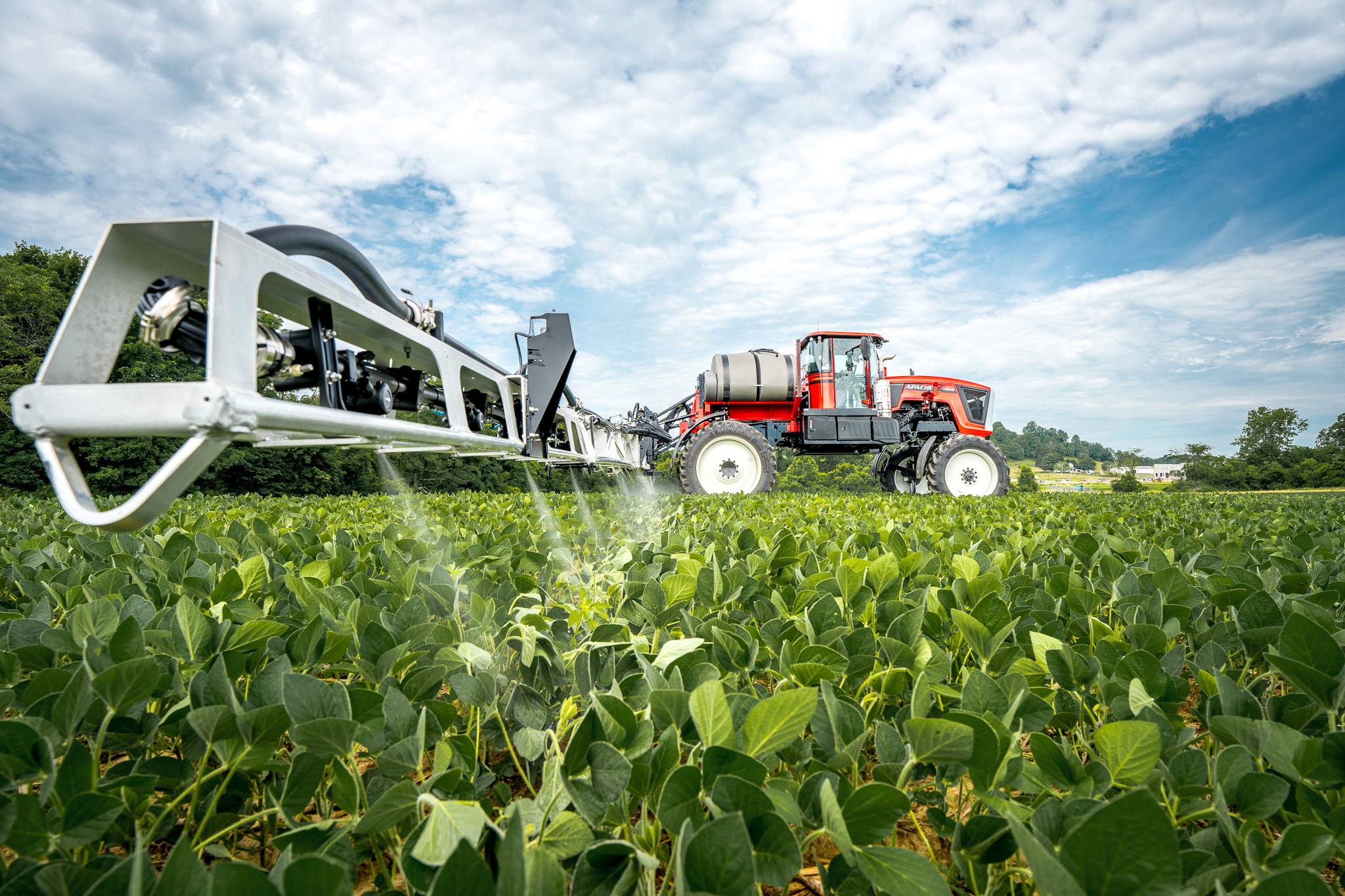 low angle of apache sprayer with booms extended, spraying into field